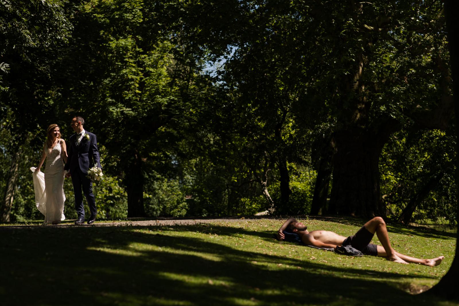 Bruidspaar loopt langs zonnende man in park Rotterdam