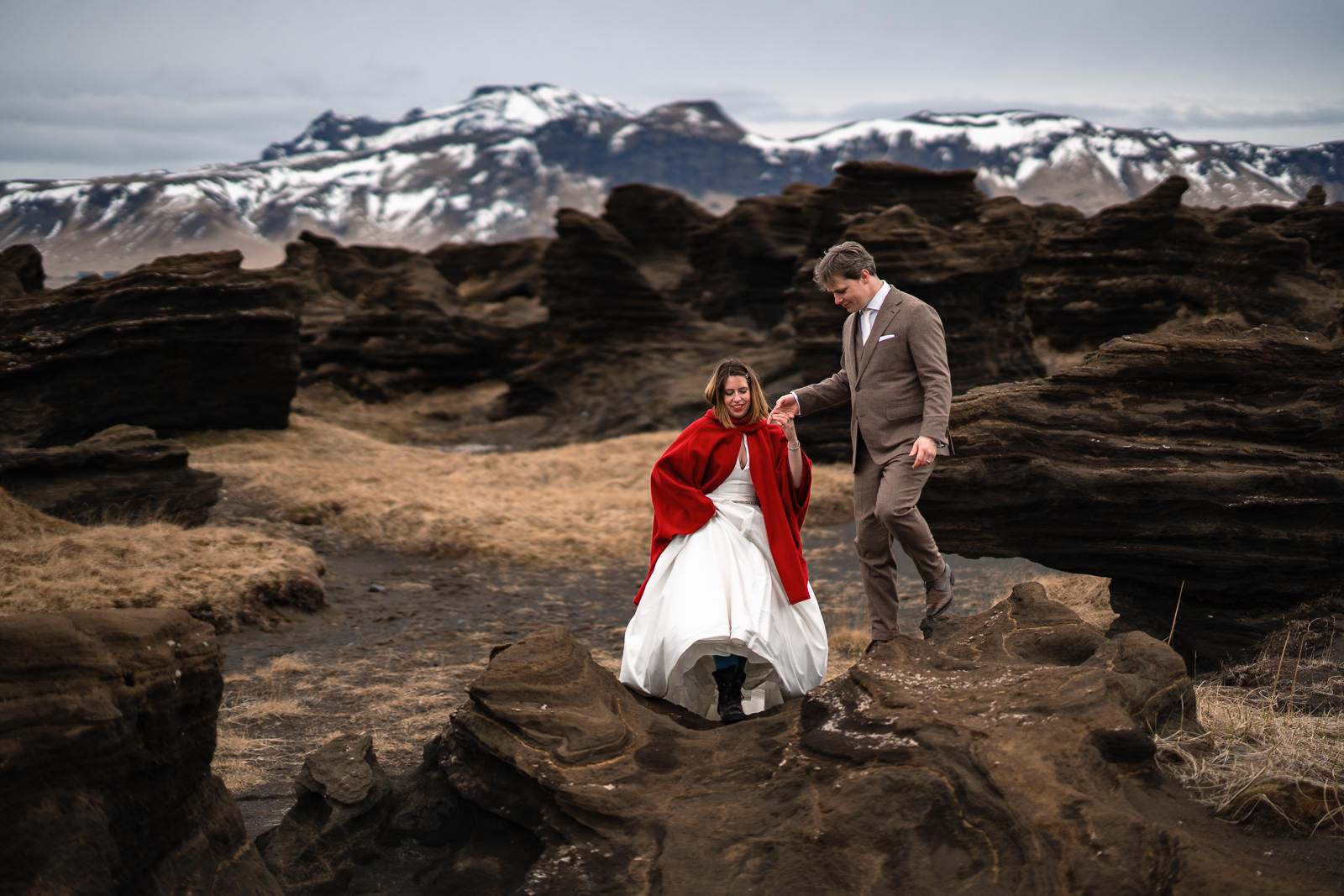 After Wedding shoot in IJsland bruidspaar wandelend door epic lavalandschap met bergen op de achtergrond met Trouw Fotograaf Paco van Leeuwen